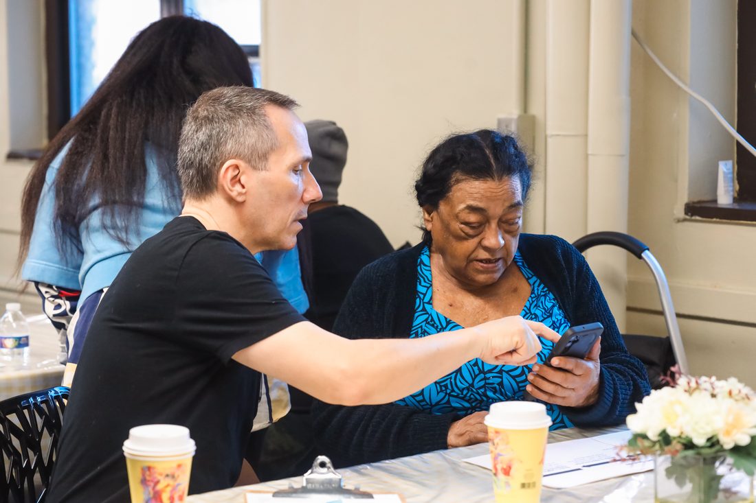 A volunteer points out a feature on a senior's phone