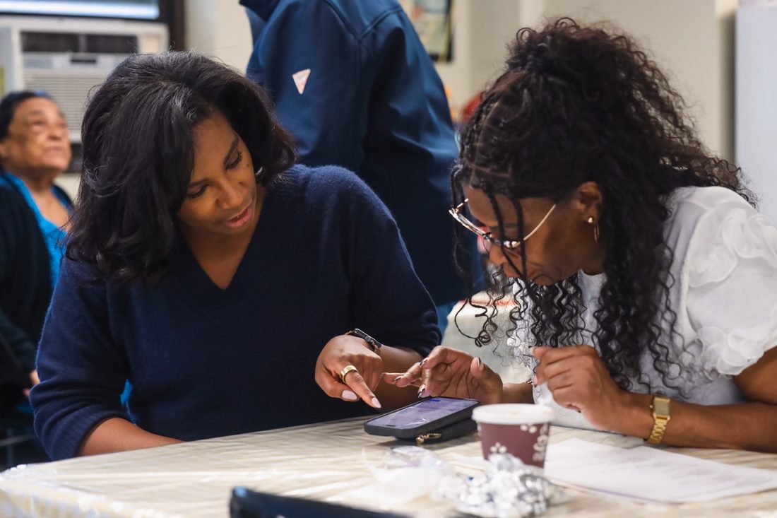 Two volunteers compare notes on a phone