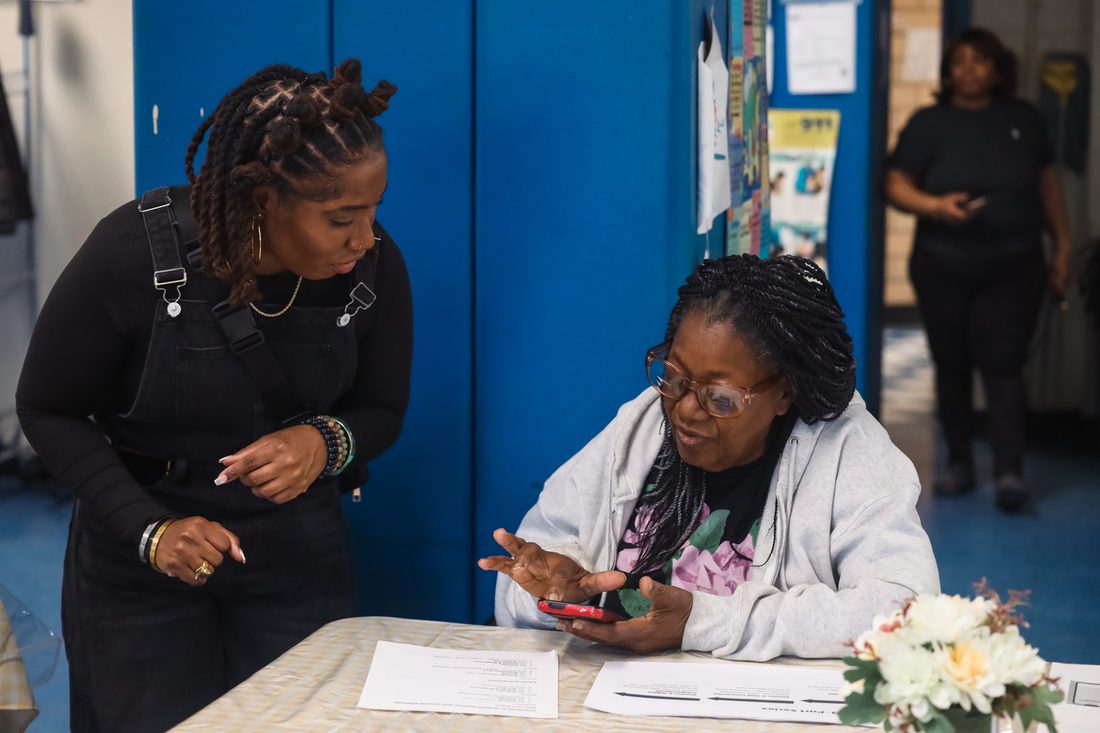 Kimberly Gant helping a senior workshop participant with her phone