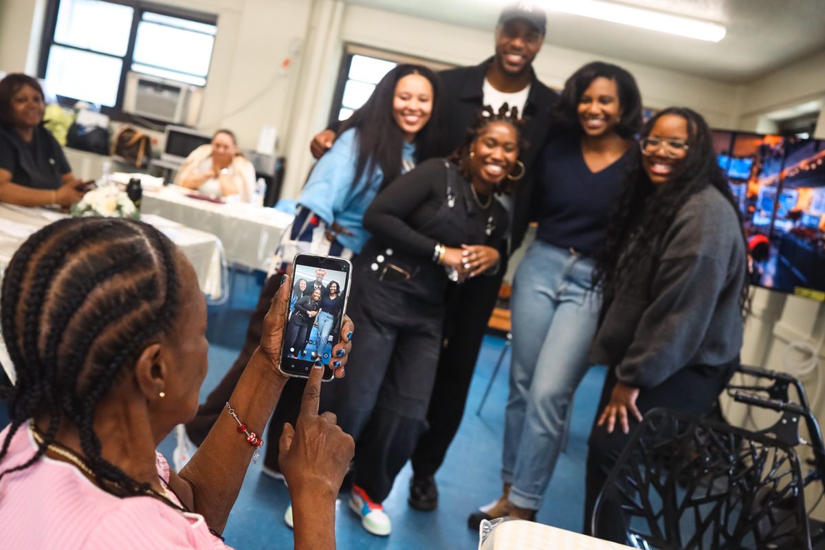 A senior takes a group photo of volunteers and staff